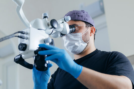 Caucasian male adult using medical microscope in laboratory with protective gear
