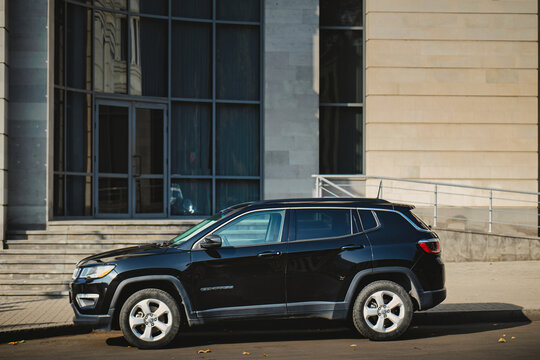 A black Jeep compass is parked in front of a building