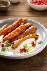 Roasted baby carrots on plate close up wooden surface