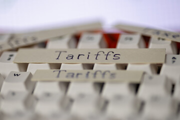 economic tariffs concept on a keyboard. close-up shot of paper strips with the word tariffs, symbolizing global trade, business, and political issues