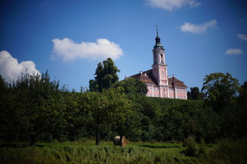 The Baroque style Birnau Basilica surrounded by vineyards and tress against the background of blue sky. Nussdorf, Lake Constance, Germany.