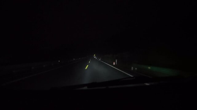 POV night driving passing flashing yellow warning lights on roadside. Construction or hazard zone at night.