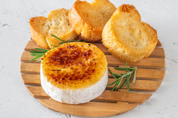 Flamed Camembert with caramelized golden sugar crust and fresh rosemary on board