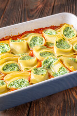 Golden baked lumaconi filled with ricotta and spinach resting in rich tomato sauce