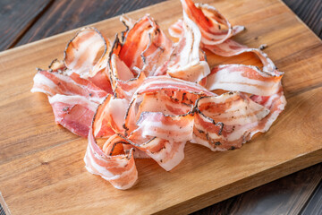 Rustic presentation of sliced Italian pancetta arranged neatly on wooden cutting board