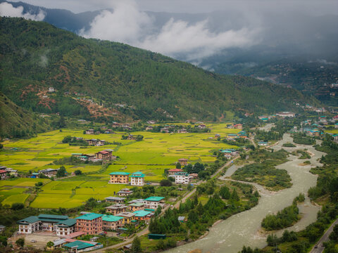 Aerial view of the river, valley, vibrant rice fields and a flowing river against a backdrop of verdant mountains, Paro, Bhutan.