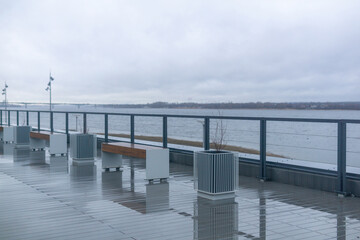 Fototapeta premium Empty benches on the embankment by the river in rainy day