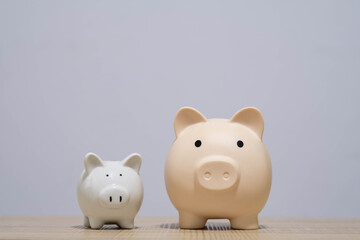 Two piggy banks in different sizes on a wooden with a clean background symbolizing savings growth, money comparison, budgeting, financial planning, investment, personal finance for business content.