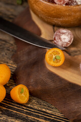orange jam made from oranges and citrus fruits and dried in syrup, whole kumquat fruits in white powder, a glass jar with sweet orange jam is on the table