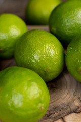 green ripe citrus limes scattered on a wooden table in the kitchen, ripe and juicy lime for cooking both sauces and drinks and other food