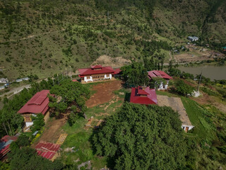 Aerial view of Chimi Lhakhang, a monastery with red roofs nestled among rolling hills, evokes a sense of peace and spiritual harmony, Teoprongchu, Punakha, Bhutan.