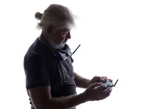 silhouette of bearded elderly man setting up a drone flight with remote controller, studio shot of progressive person interested in modern technologies