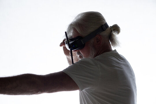 silhouette profile of bearded elderly man in googles on his head extended hand forward leaving the frame, virtual reality and modern technologies concept
