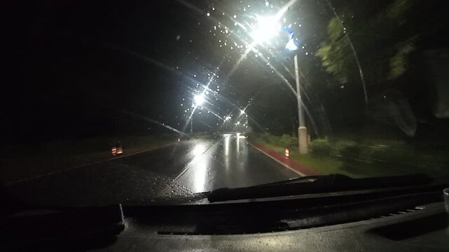 4K POV night driving through scratched windshield with street light glare. Abstract and moody atmosphere depicting fatigue or astigmatism.