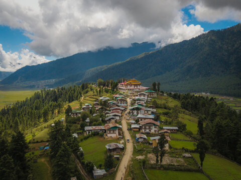 Aerial view of Gangtey Monastery perched atop a hill, overlooking the lush green Phobjikha Valley under a cloudy sky, Gangtey village, Wangdue Phodrang, Bhutan.