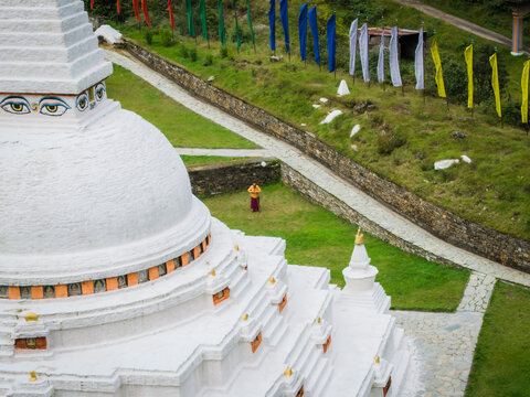 Aerial view of the white Chendebji Chorten Stupa with its watchful eyes, contrasted against the green landscape and colorful prayer flags, Chendebji village, Trongsa, Bhutan.