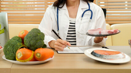 professional nutritionist in uniform writing notes on the table with different healthy products and drawings on the topic of healthy eating