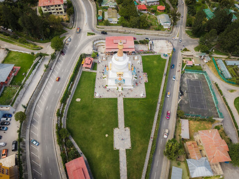 Aerial view of the National Memorial Chorten's white stupa rising from the green lawn, framed by roads and buildings, Thimphu, Bhutan.