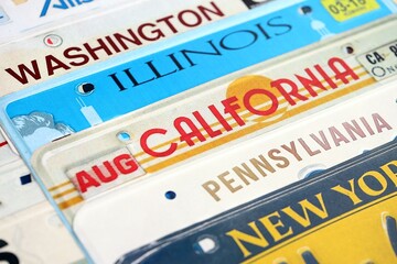 Old US car license plates with various state names. Concept of driving in United States. Reaching a car registration