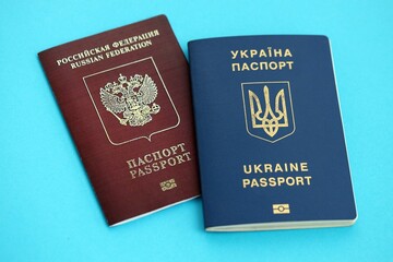 Ukraine and Russian Federation passports on light blue table background close up. Concept of...