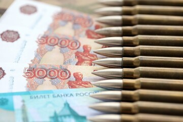 Russian money with bullets on multicam camouflage fabric close up. Concept of russian army funds and invasion to Ukraine