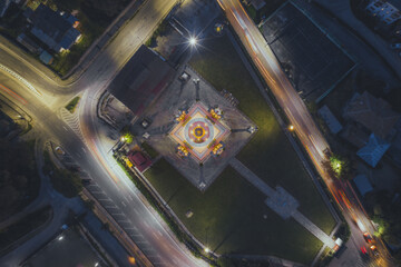 Aerial view of the illuminated National Memorial Chorten radiates warmth against the cool night, framed by the flowing lights of surrounding traffic, Thimphu, Bhutan.