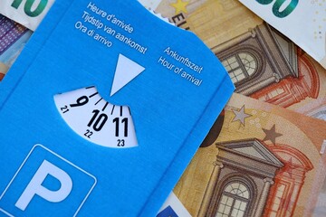 European parking disc with time dial on many euro money bills banknotes close up. Concept of disc parking system in europe