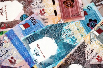 Qatari riyal money bills banknotes lies in big pile on table close up. Concept of finances and...