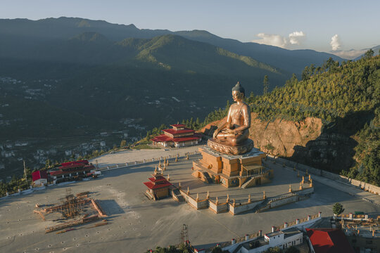 Aerial view of the golden Buddha Dordenma statue meditating peacefully against a backdrop of lush green mountains and clear skies, Thimphu, Thimphu, Bhutan.