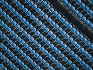 Aerial view of rows of empty blue stadium seats casting stark shadows, creating a geometric pattern of light and shade, Thimphu, Bhutan.