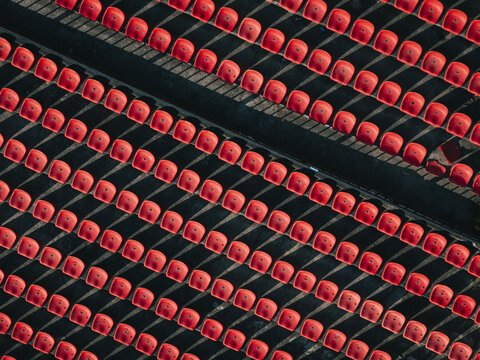 Aerial view of rows of vibrant red stadium seating casting stark shadows, creating a mesmerizing geometric pattern from above, Thimphu, Bhutan.