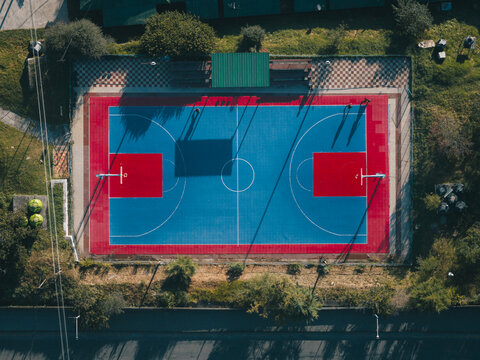 Aerial view of a vibrant basketball court with its bold blue and red surfaces standing out against the surrounding greenery, Thimphu, Bhutan.