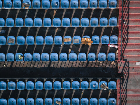 Aerial view of rhythmic rows of blue seats contrast sharply with the red steps, shadows creating bold patterns, Thimphu, Bhutan.