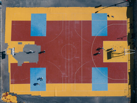 Aerial view of a vibrant basketball court painted in bold blocks of yellow, red, and blue, creating a striking geometric pattern from above, Thimphu, Bhutan.