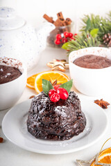 Traditional English Christmas pudding mug cake. Simple Christmas pudding recipe idea, made on tea mug with microwave, portioned Christmas pudding with sugar powder and cranberry festive decor