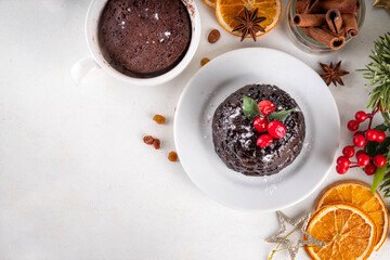 Traditional English Christmas pudding mug cake. Simple Christmas pudding recipe idea, made on tea mug with microwave, portioned Christmas pudding with sugar powder and cranberry festive decor
