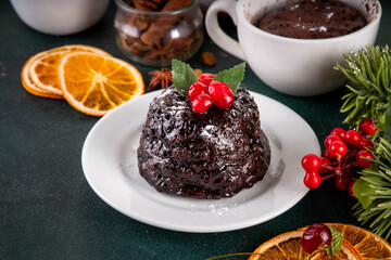 Traditional English Christmas pudding mug cake. Simple Christmas pudding recipe idea, made on tea mug with microwave, portioned Christmas pudding with sugar powder and cranberry festive decor