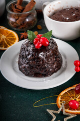 Traditional English Christmas pudding mug cake. Simple Christmas pudding recipe idea, made on tea mug with microwave, portioned Christmas pudding with sugar powder and cranberry festive decor