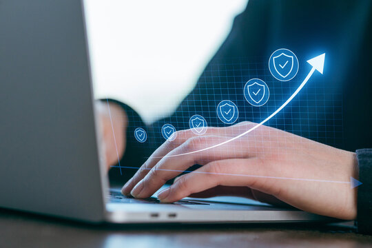 Hands typing on laptop with digital security symbols and growth trends during a business meeting