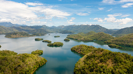 Aerial drone of lake and islands among mountains and hills against the blue sky and clouds. Randenigala reservoir, Sri Lanka.