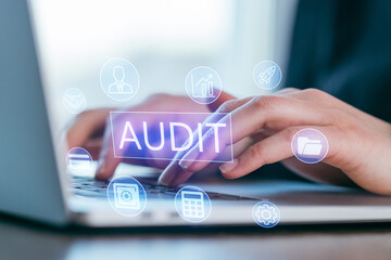 Hands using a laptop with digital icons representing audit and business analysis tasks in a modern office environment