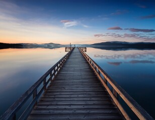 Fototapeta premium long wooden pier stretching into calm reflecting water at dawn dusk