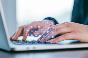 Person using a laptop with a digital calendar interface showing the days of the month
