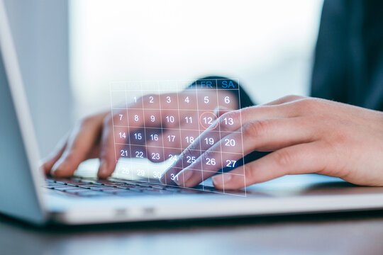 Person using a laptop with a digital calendar interface showing the days of the month - Powered by Adobe