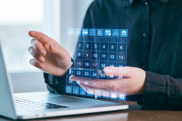 Virtual calendar displayed while a person interacts with a laptop, showcasing digital organization in a modern workspace setting