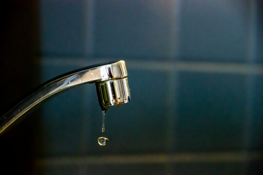 Precious water slowly dripping from a leaky faucet