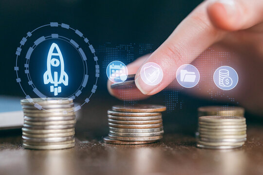 Hands placing a coin on a stack of coins with digital financial icons in a modern workspace