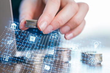 Hand stacking coins with digital financial icons and technology backdrop in a modern workspace