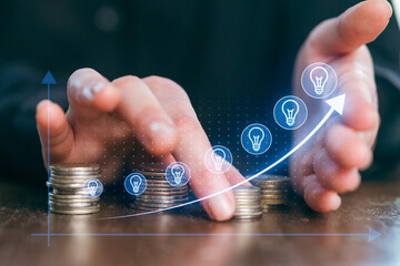 Hands arranging coins with light bulb icons illustrating growth in savings and innovative thinking