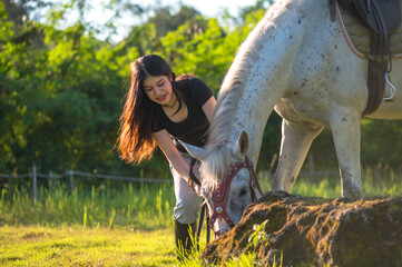 Attractive Asian equestrian enjoying with horse in ranch